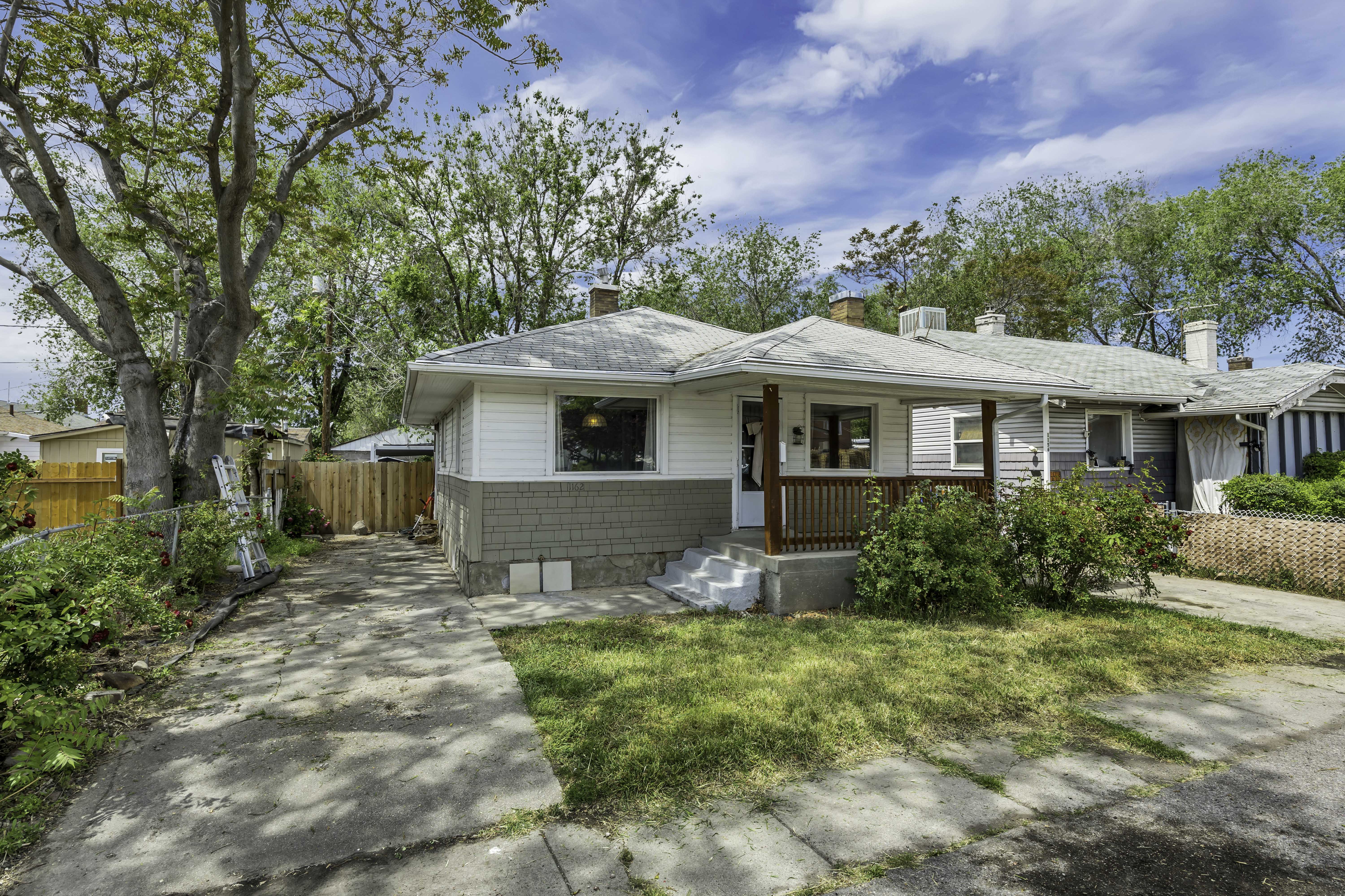 Exterior featuring white siding, a shingled roof, and a front porch with natural wood railings