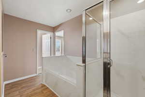Bathroom featuring a built-in tub with a white surround and an adjacent glass-enclosed shower with white paneling