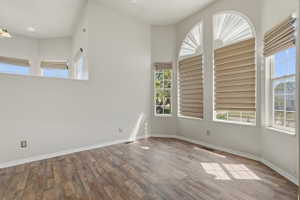 Vaulted ceiling interior featuring wood-finish flooring, multiple windows with blinds, and transom windows