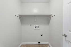 Dedicated laundry area featuring a built-in shelf, neutral wall tones, tile flooring, and a white paneled door with brushed nickel hardware