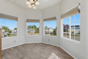 Bay window area featuring five windows with blinds, a multi-light chandelier, and wood-finish flooring