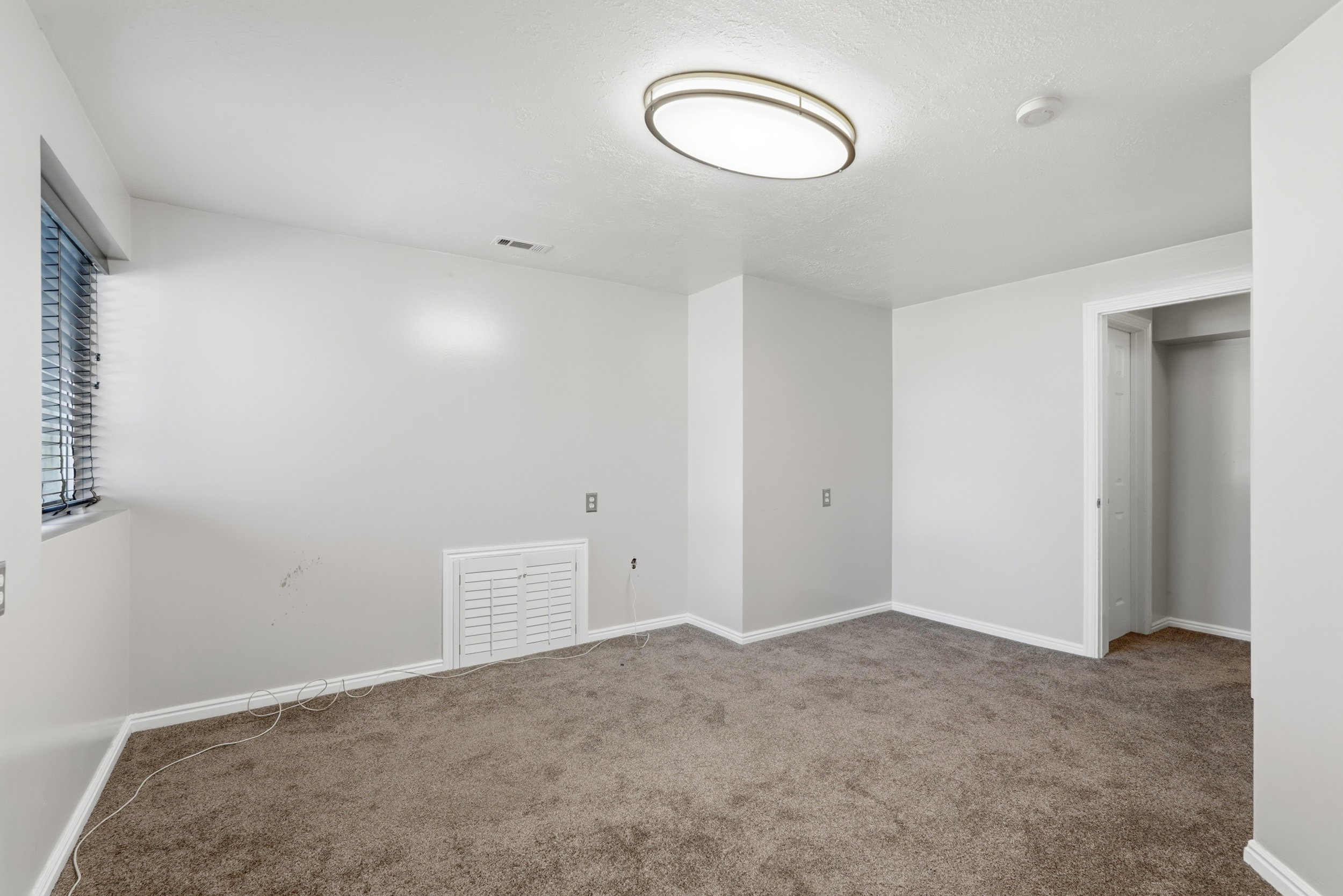 Carpeted room with a window, baseboard trim, and a built-in closet with a bi-fold door