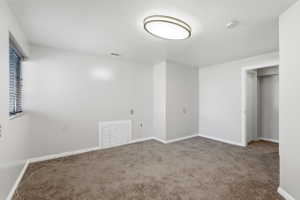 Carpeted room with a window, baseboard trim, and a built-in closet with a bi-fold door