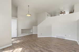 Vaulted ceiling living space featuring wood-finish flooring, a built-in wall niche, and a contemporary pendant light fixture
