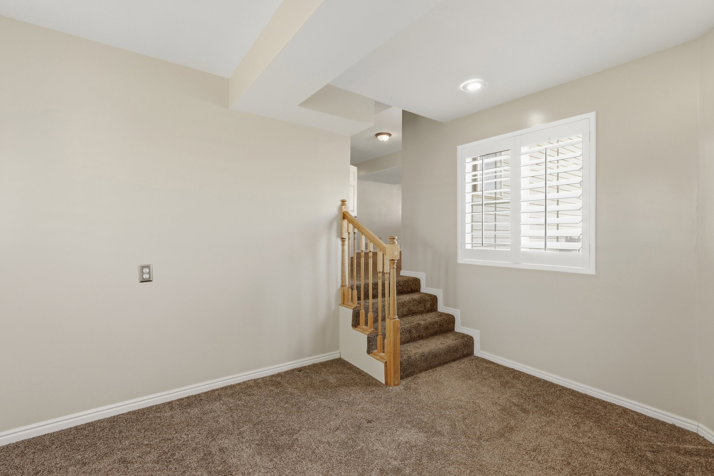 Staircase featuring wood railings and carpeted treads