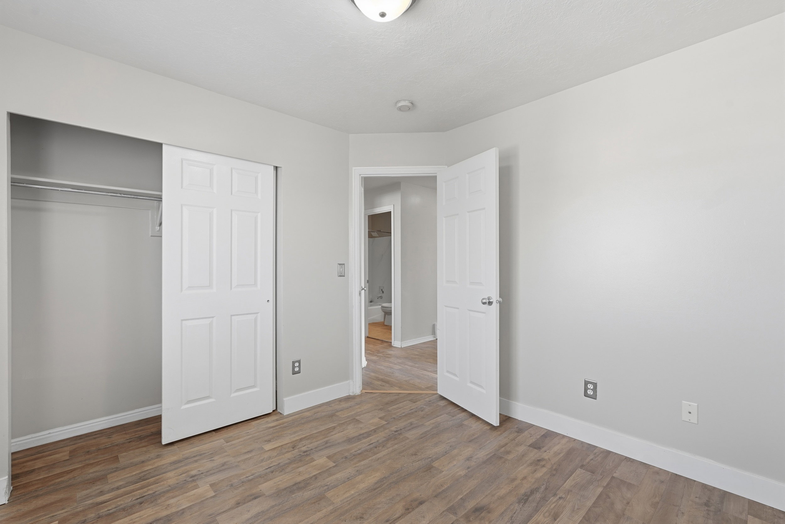Interior room featuring wood-finish flooring, light grey painted walls, and white baseboards