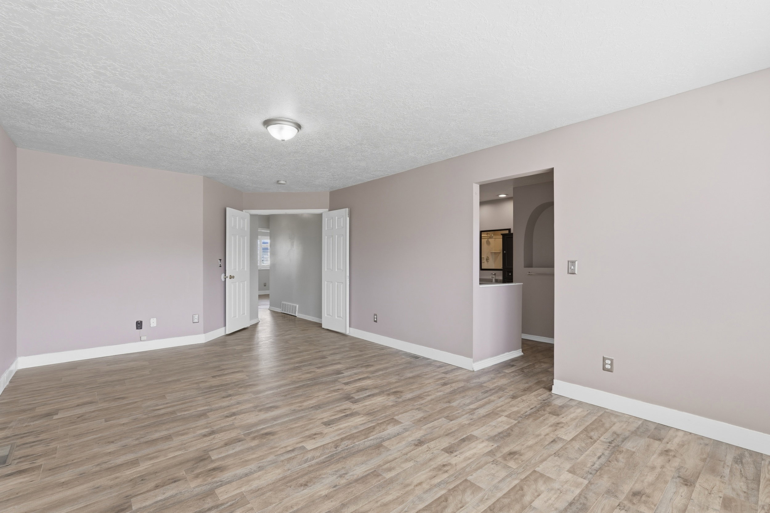 Open-concept room featuring wood-finish flooring, light-toned walls, and white trim