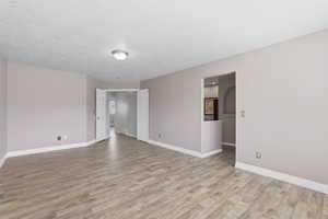 Open-concept room featuring wood-finish flooring, light-toned walls, and white trim