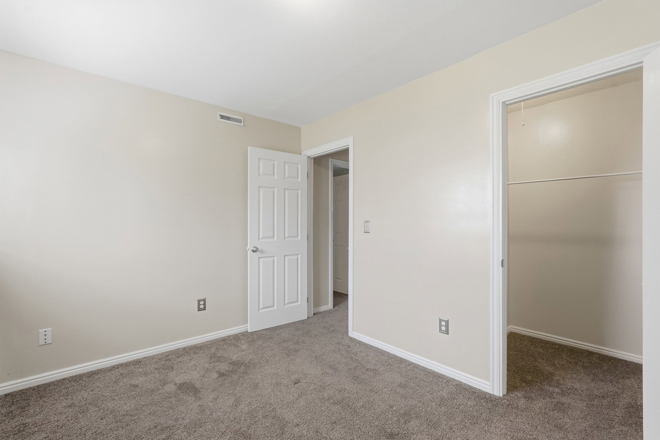 Neutral-toned room featuring light gray carpeting and white baseboards
