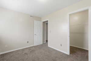 Neutral-toned room featuring light gray carpeting and white baseboards