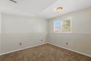 Room featuring neutral two-tone wall paint, a window with white louvered blinds, and brown carpet flooring