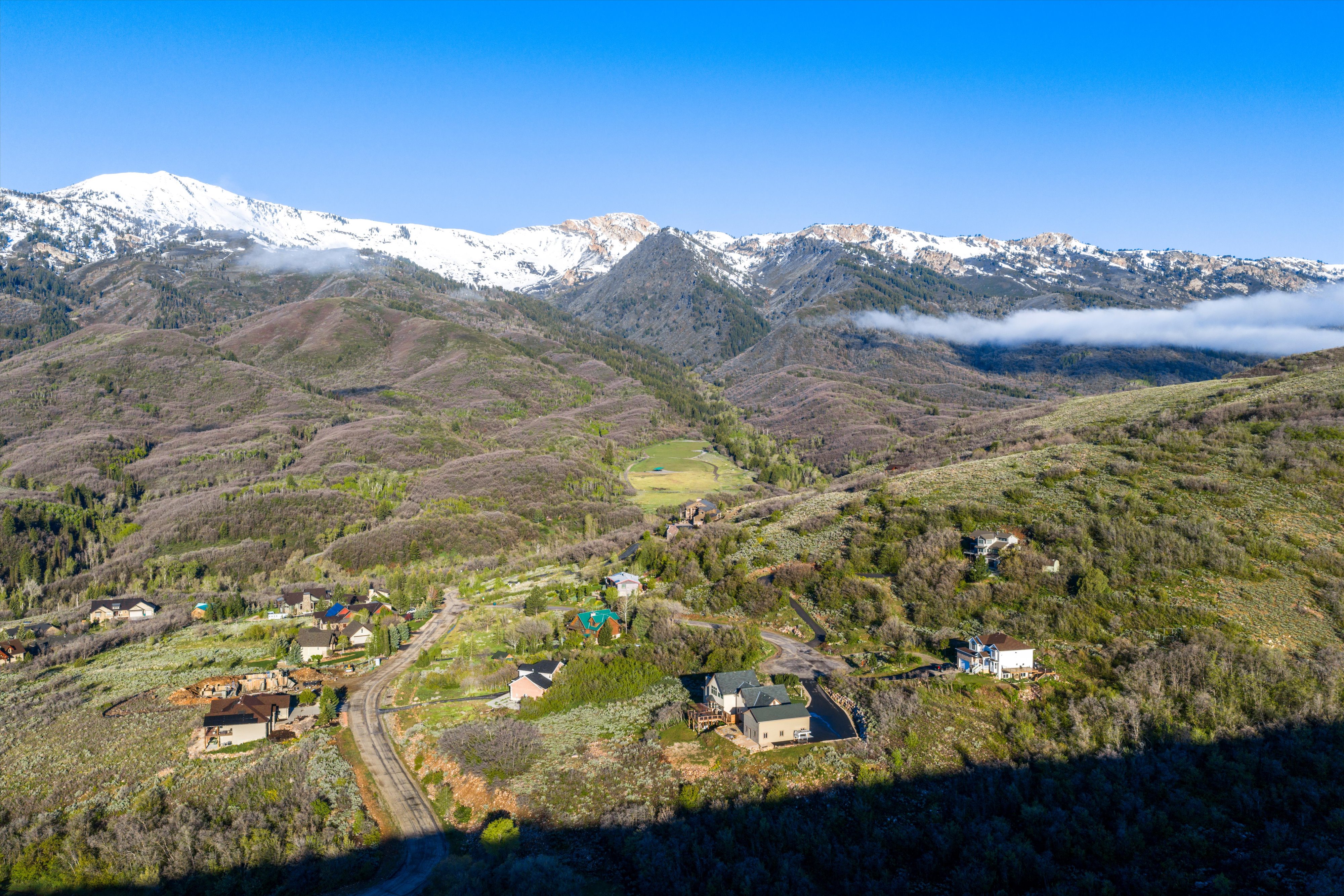 Expansive mountain landscape featuring distant snow-capped peaks and scattered residential properties