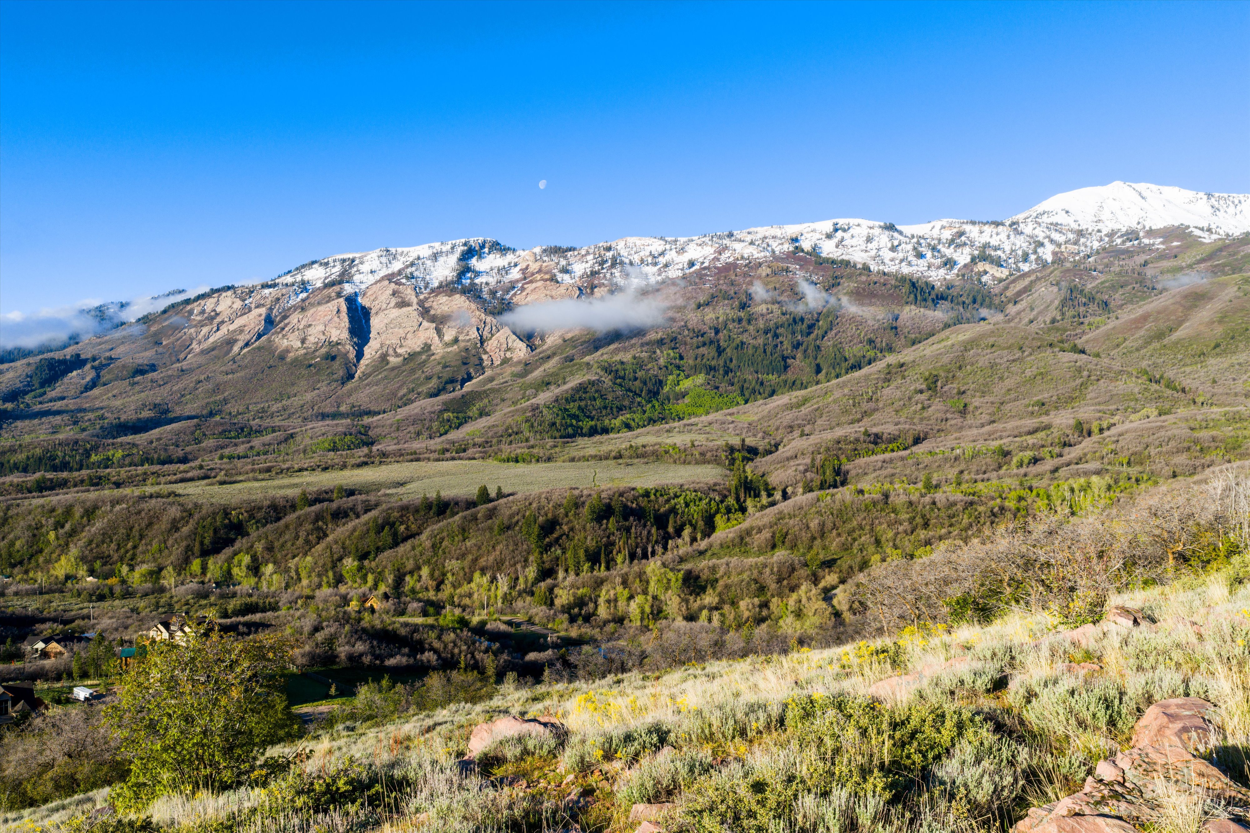 Expansive mountain landscape featuring snow-capped peaks and verdant valleys