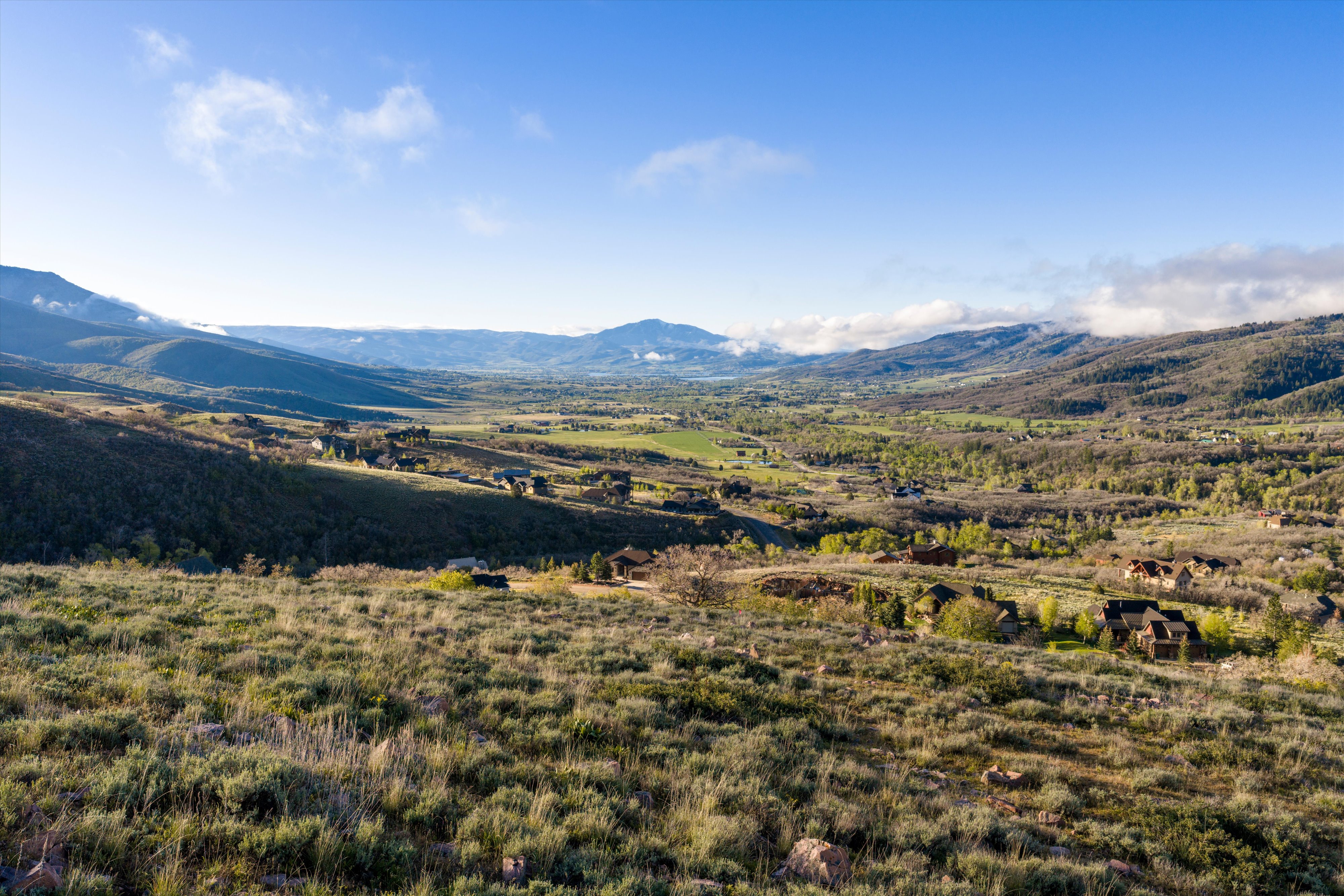 Expansive mountain landscape featuring a valley with scattered residential properties