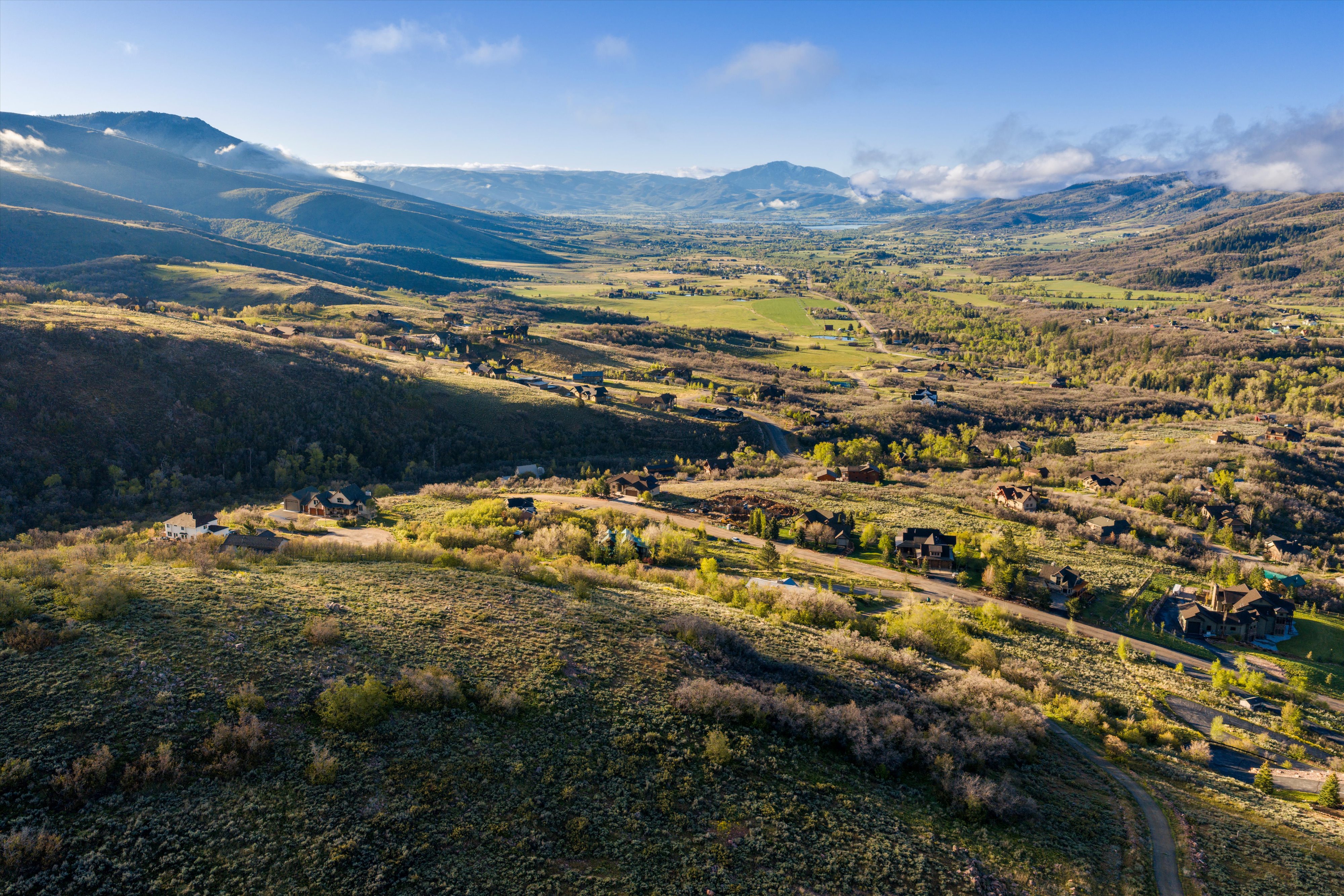 Expansive valley landscape featuring rolling hills, distant mountains, and scattered residential properties