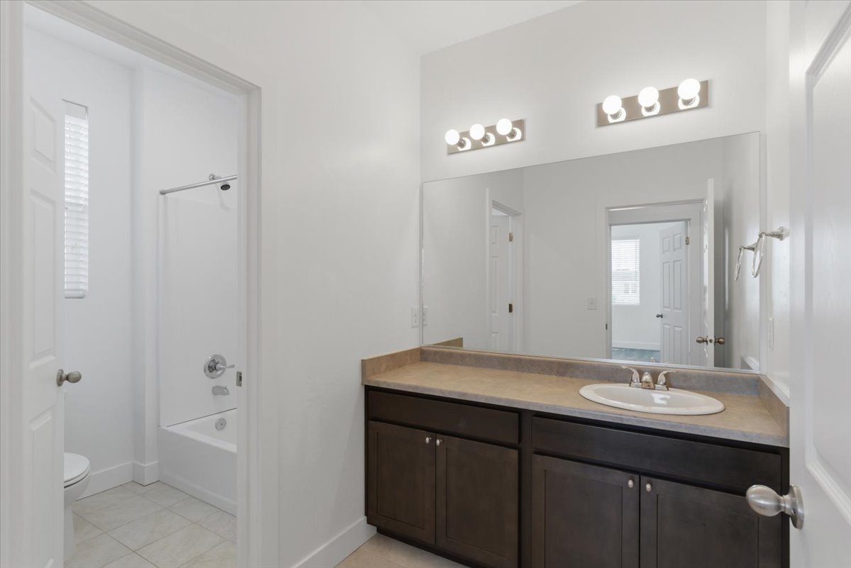 Bathroom featuring a single vanity with a white oval sink, dark wood-finish cabinetry, and a light-toned countertop