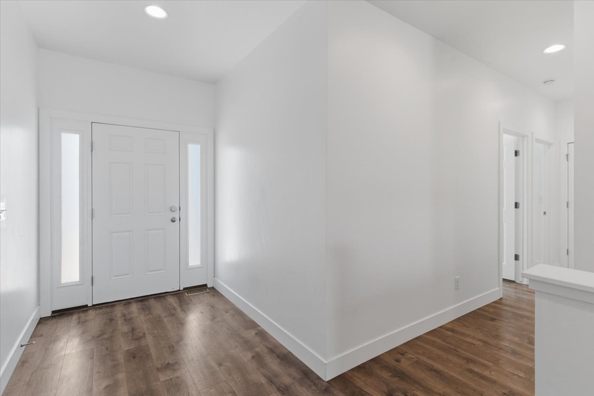 Entryway featuring a white paneled door with frosted sidelights, recessed lighting, wood-finish flooring, and crisp white walls