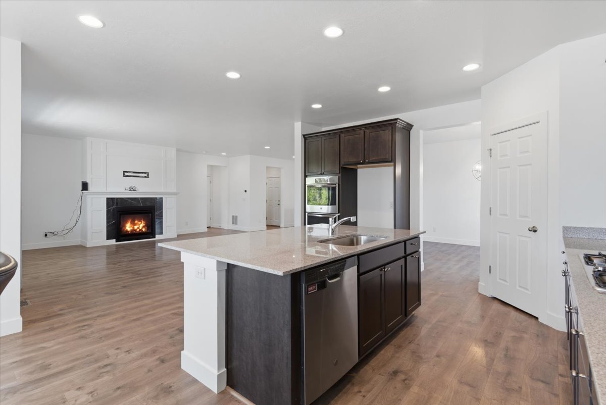 Central kitchen island featuring a double-basin stainless steel sink, integrated dishwasher, and light-toned countertop