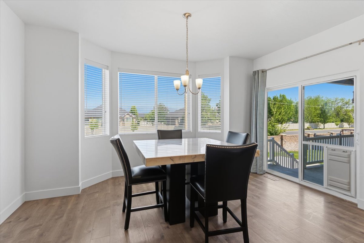 Dining area featuring wood-finish flooring, a bay window with blinds, and a sliding glass door providing access to an exterior deck