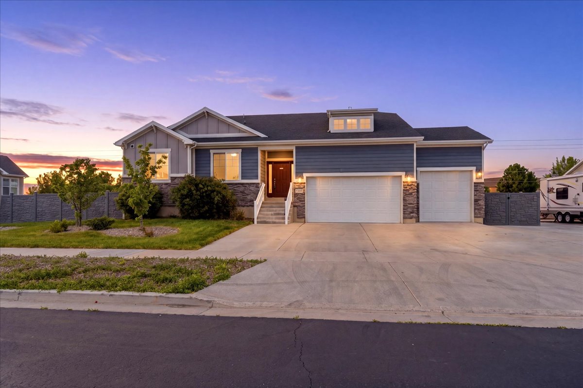 Contemporary residence featuring blue siding, stone accents, and a prominent three-car garage