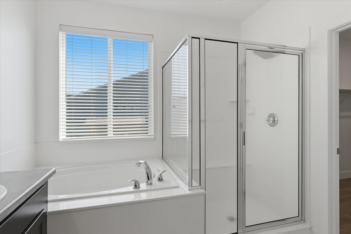 Corner soaking tub with polished chrome fixtures and a frosted glass shower enclosure