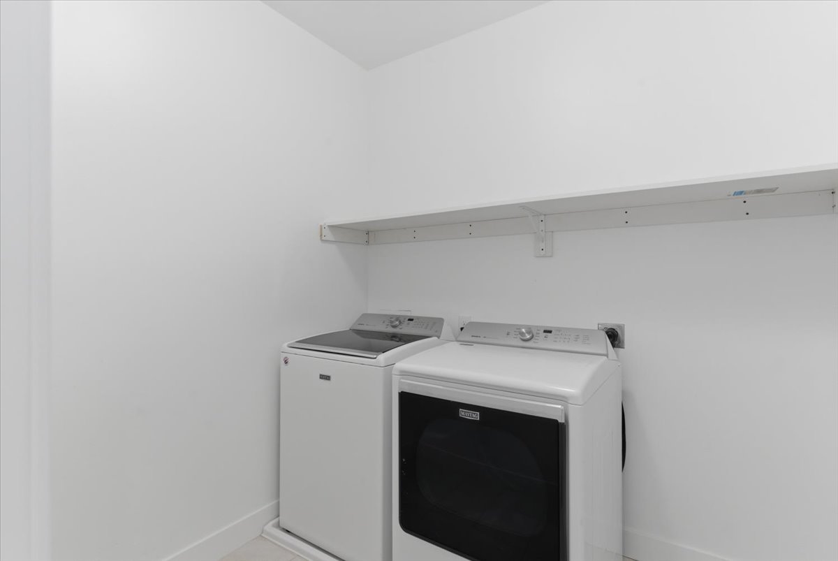 Dedicated laundry area with a white shelving unit for storage