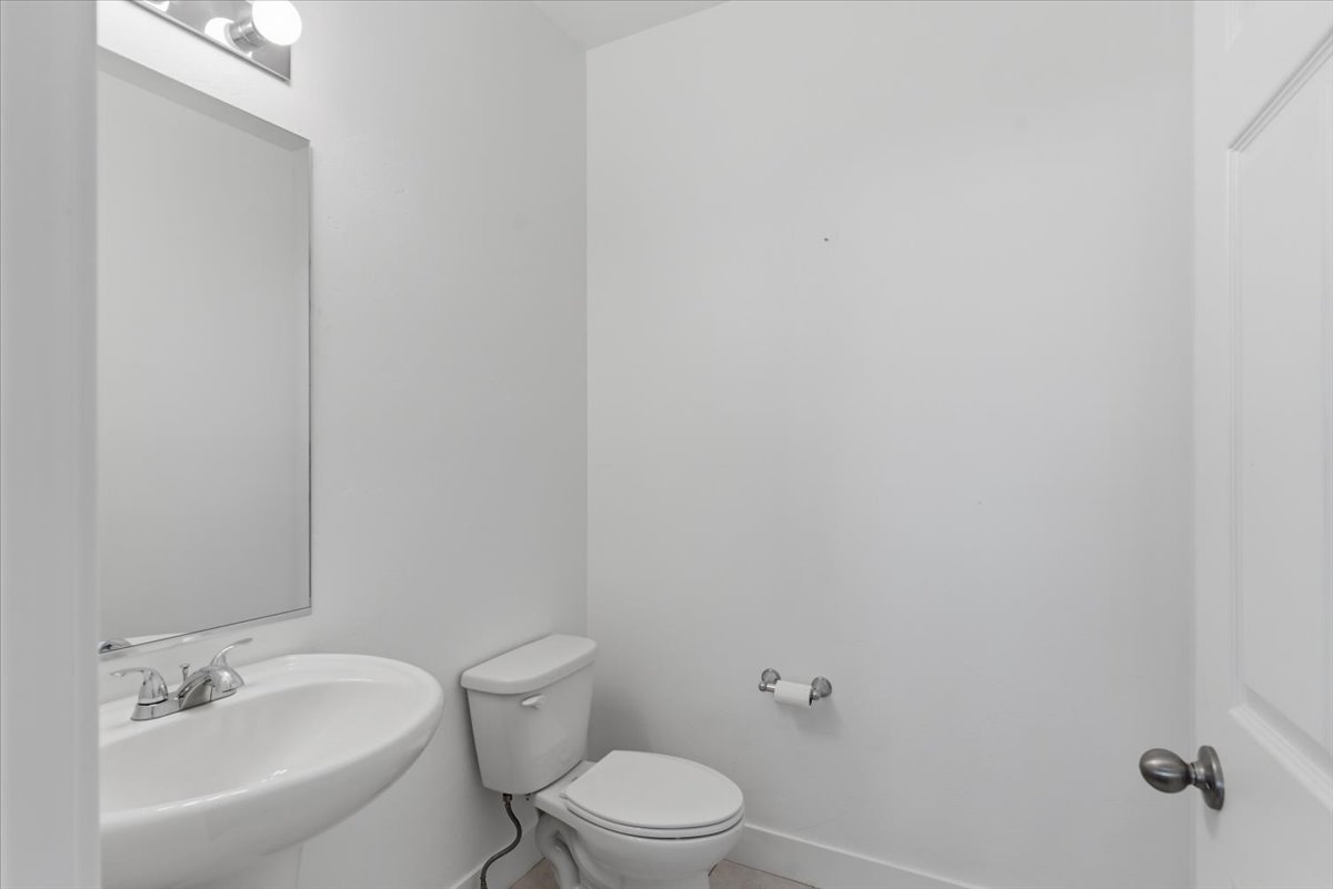 Pedestal sink with chrome faucet, large wall mirror, and vanity light fixture
