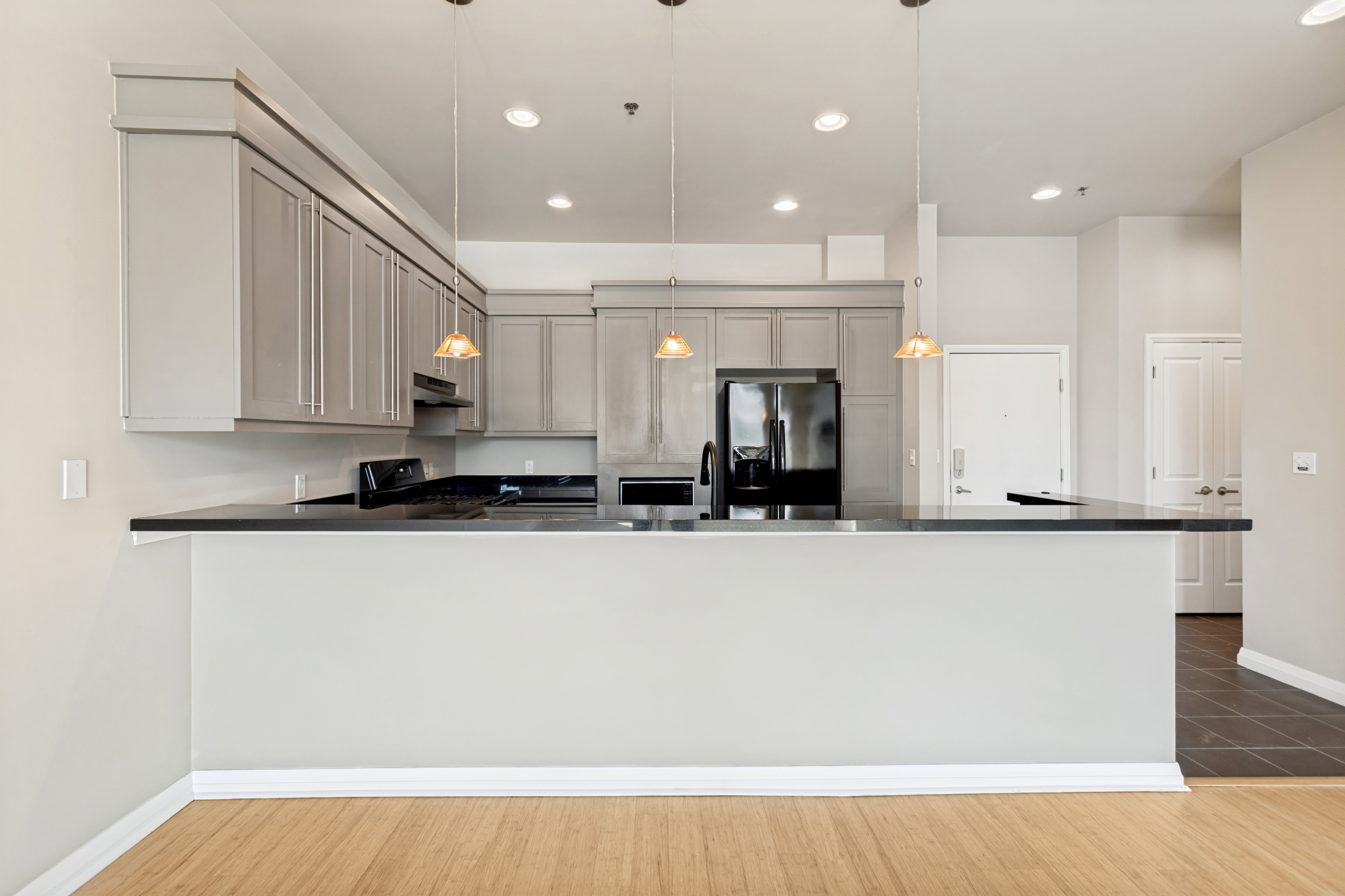 Modern kitchen featuring gray cabinetry, dark countertops, recessed lighting, and pendant fixtures
