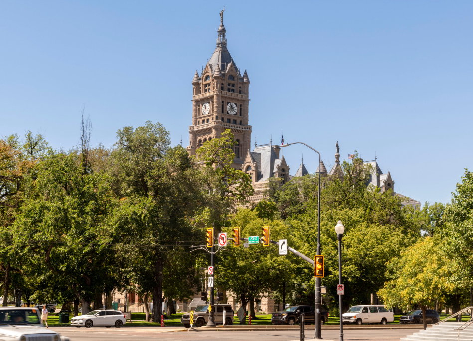 Historic stone architecture with a prominent clock tower, surrounded by mature trees