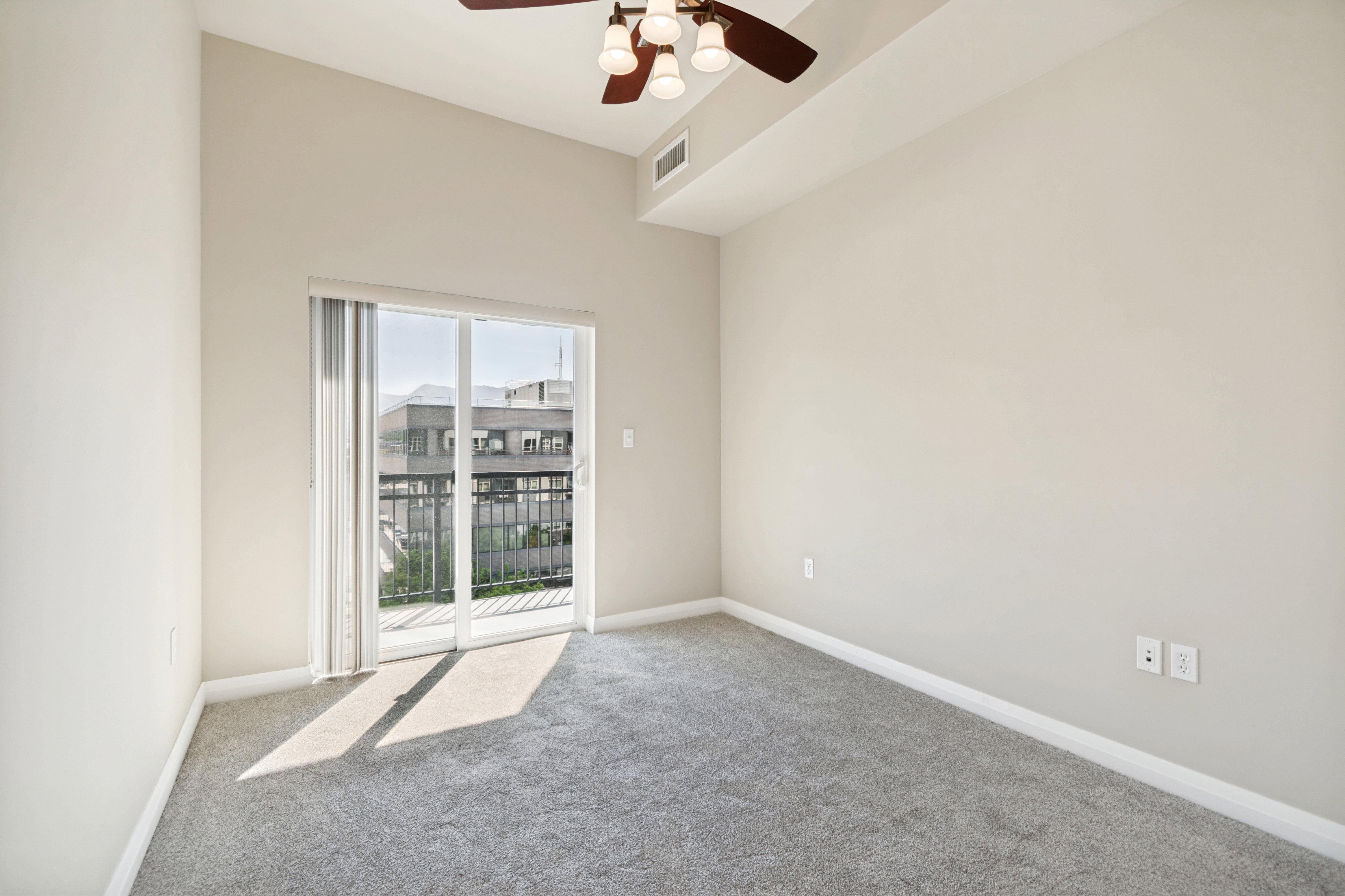 Room featuring light gray carpet, neutral painted walls, a vaulted ceiling, and a ceiling fan with integrated lighting