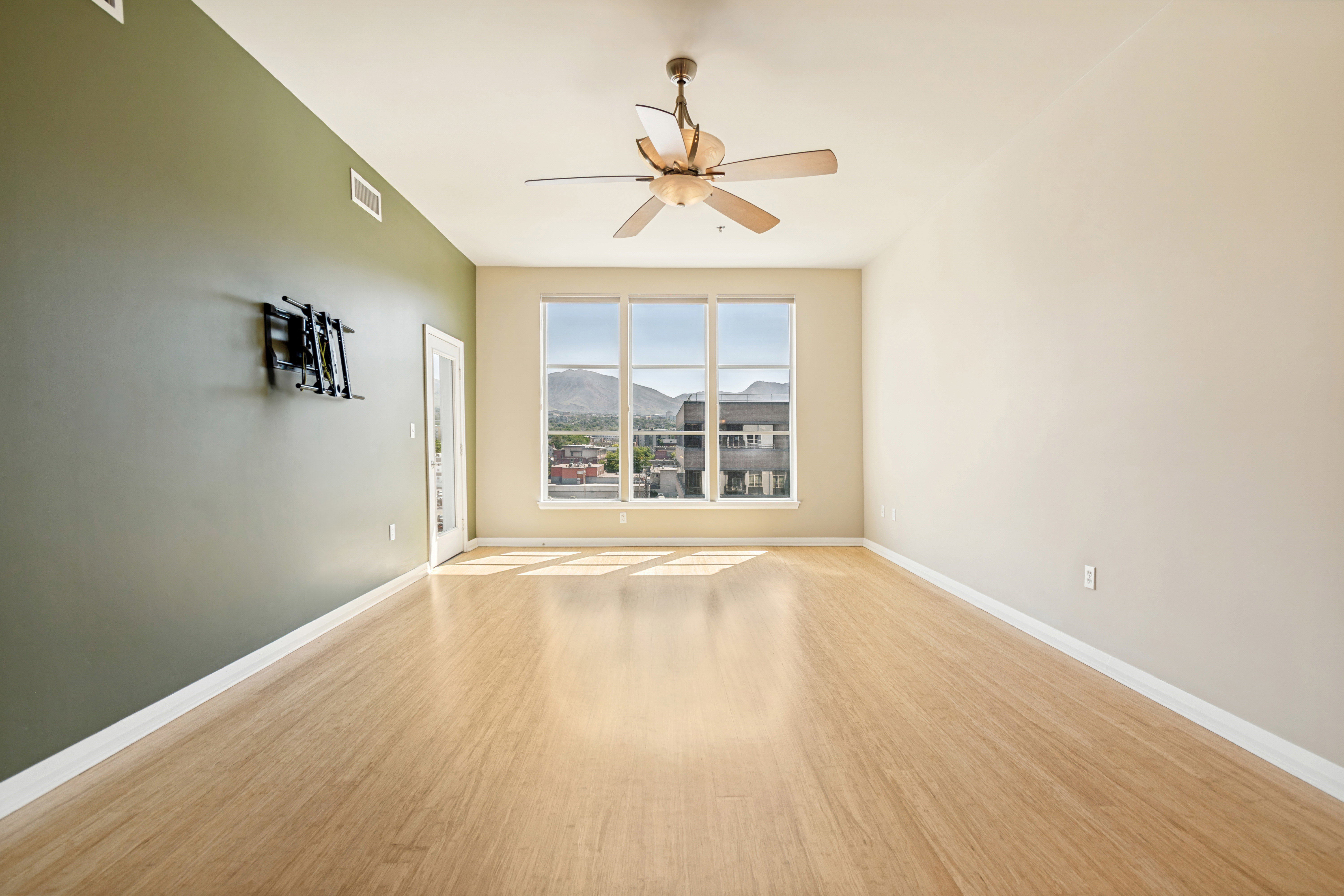 Spacious room featuring wood-finish flooring, a ceiling fan, and large windows with mountain scenery