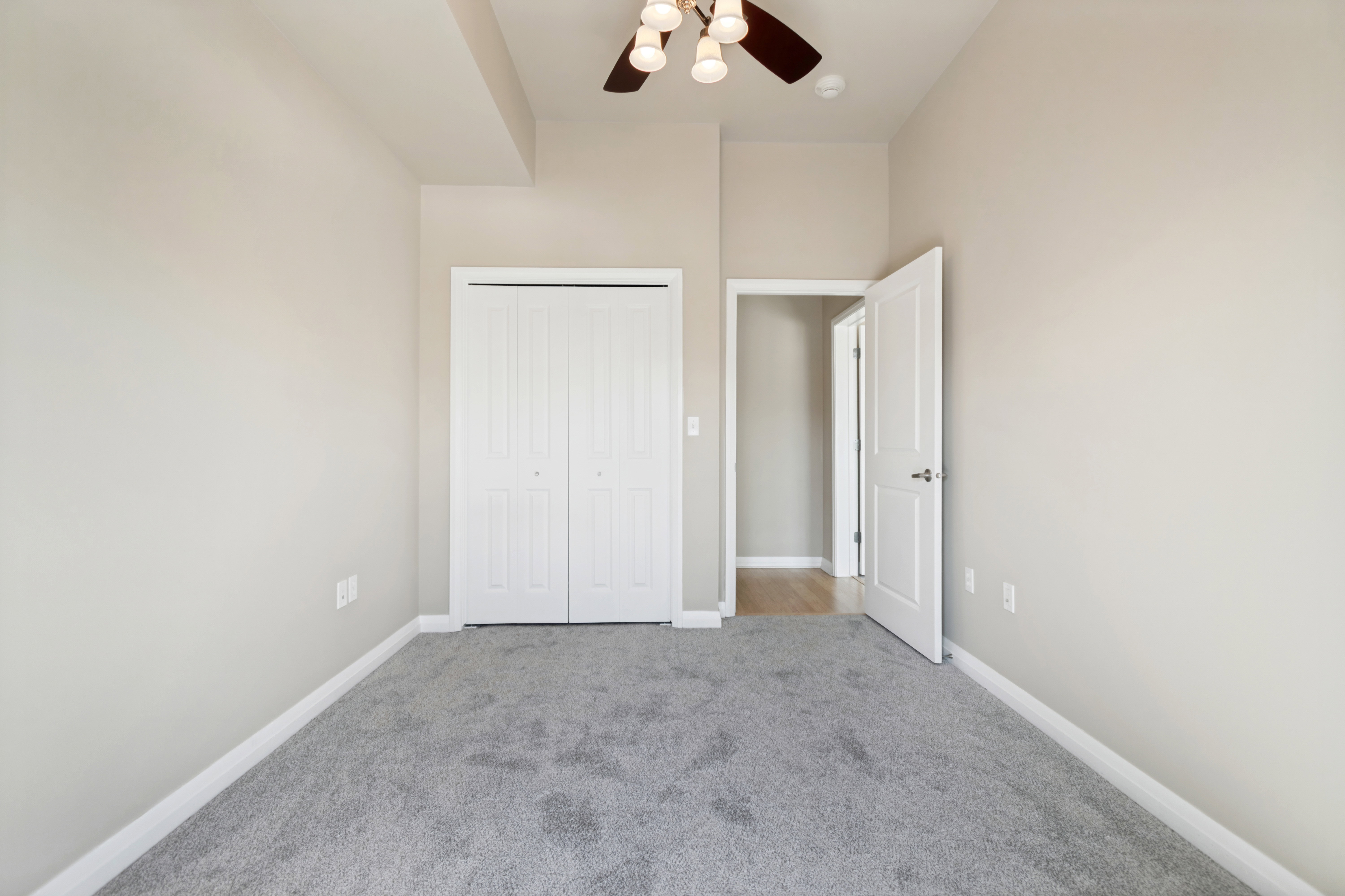 Spacious room featuring light gray carpeting, neutral wall paint, and white trim