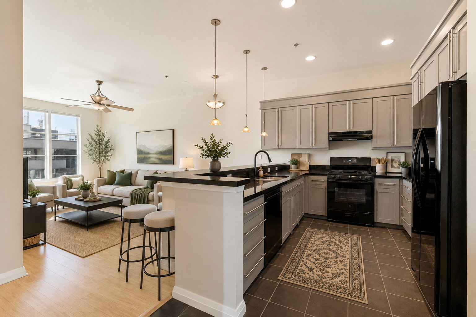 Open-concept living area featuring a kitchen with light gray cabinetry, dark countertops, and black appliances