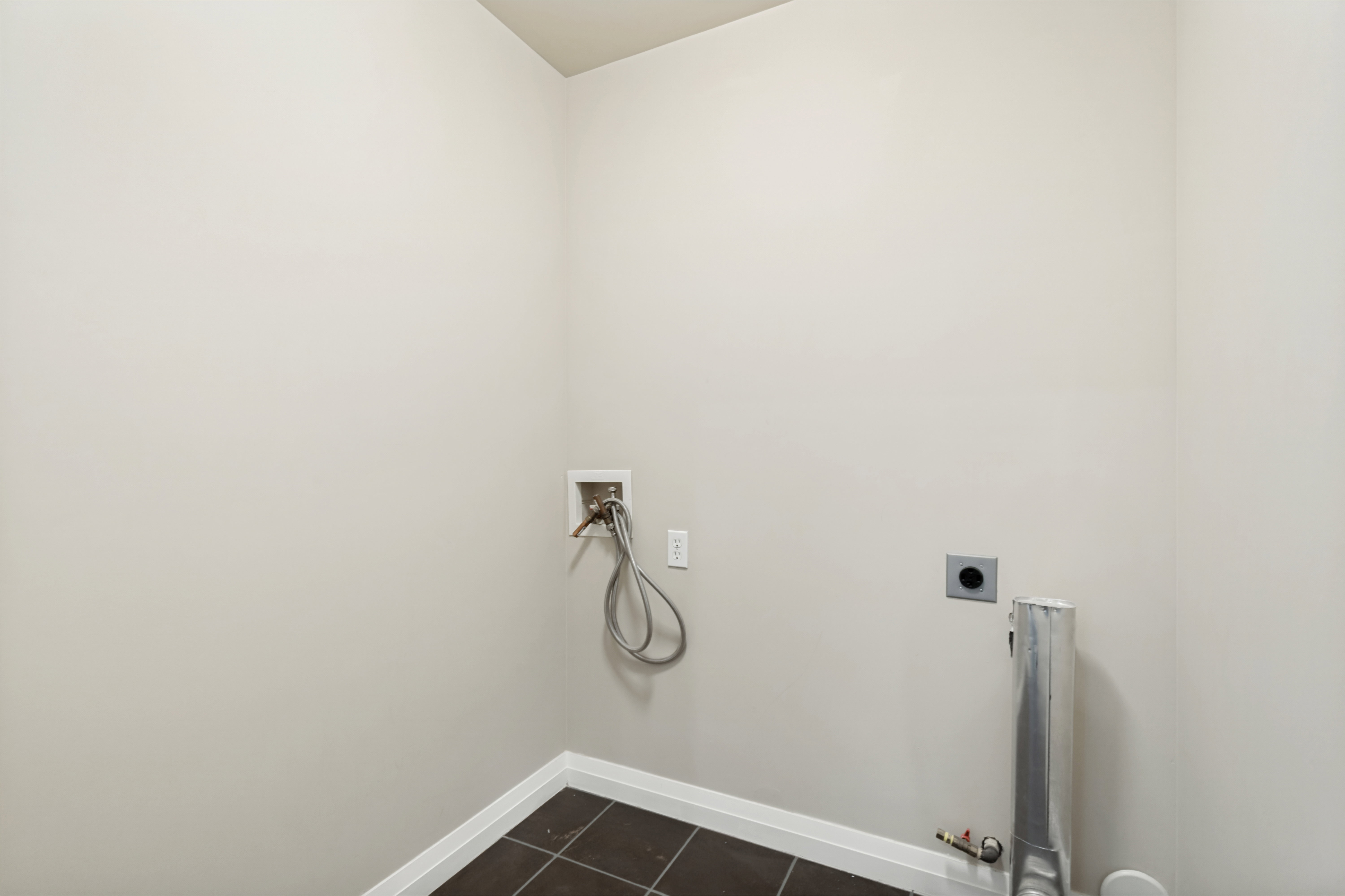 Dedicated laundry area featuring dark tile flooring and light wall finishes