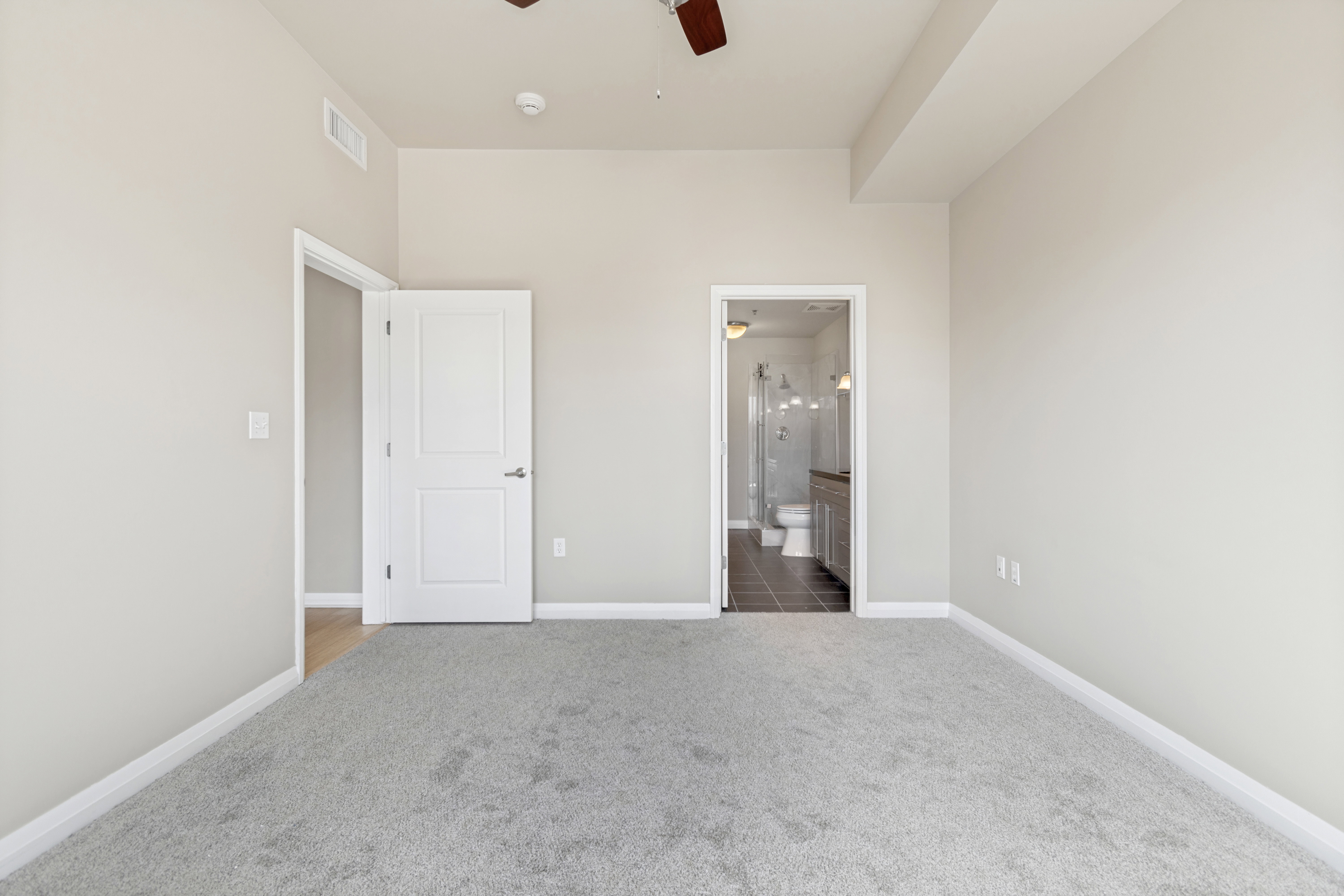 Carpeted interior space with light neutral wall tones and white baseboards