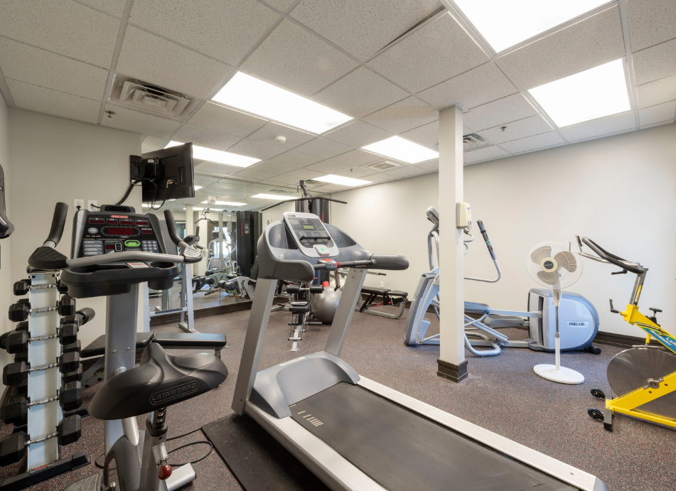 Fitness center featuring a variety of exercise equipment, mirrored wall, and recessed ceiling lighting