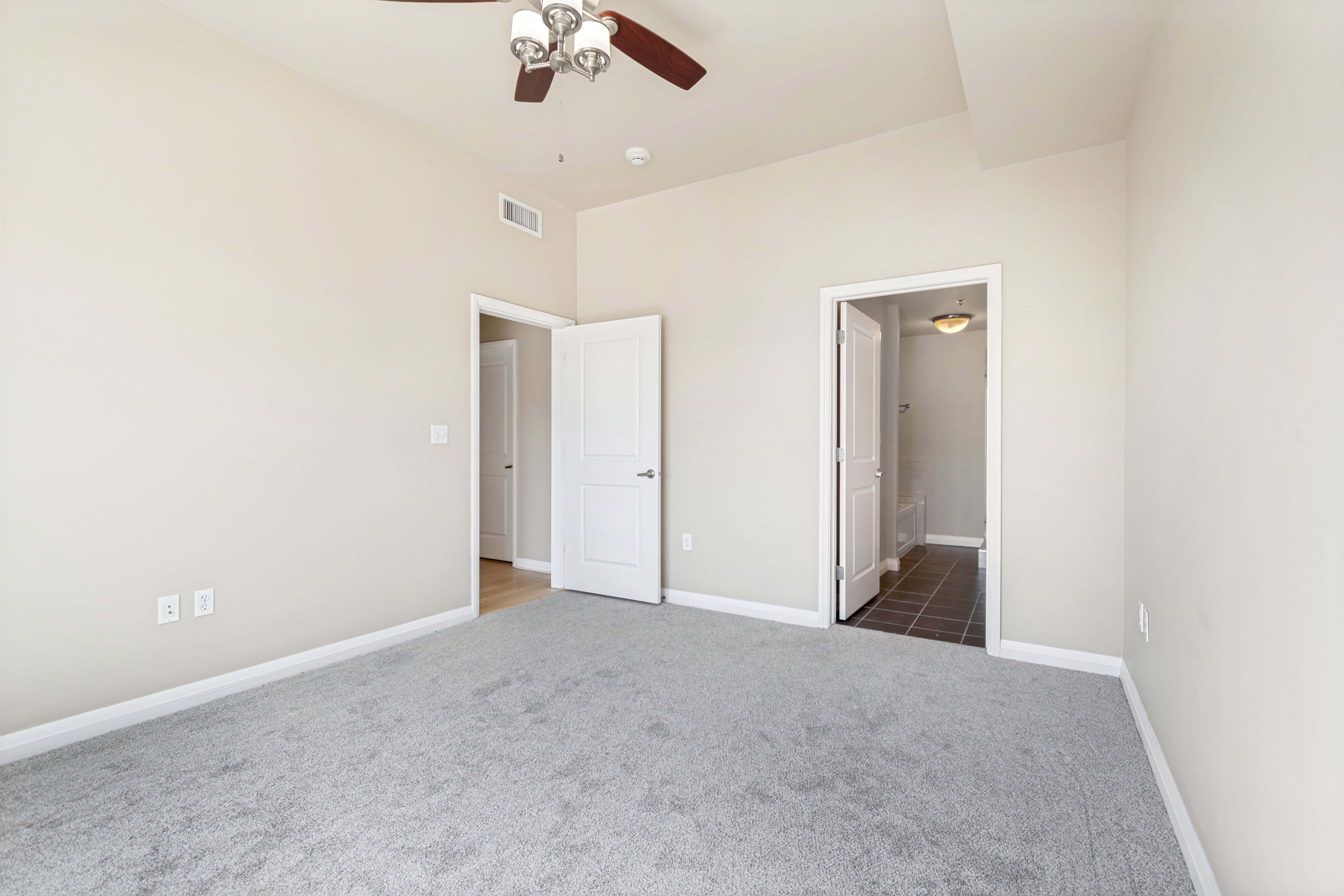 Carpeted room with vaulted ceilings and a ceiling fan with light fixture
