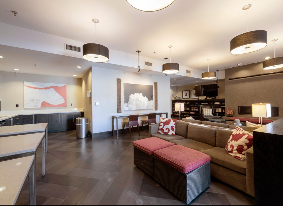 Spacious common area featuring chevron-patterned wood-finish flooring, a contemporary fireplace, and a built-in media center