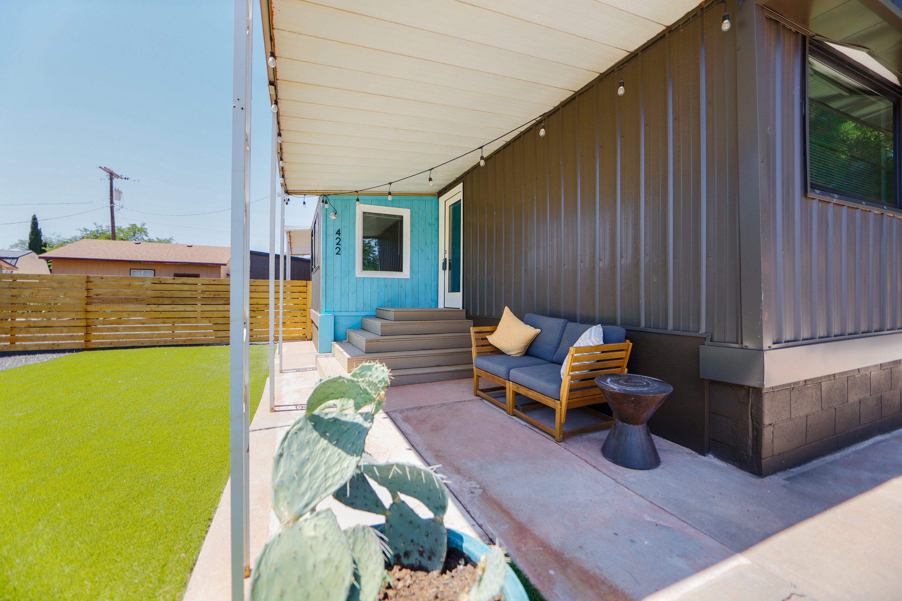 Covered patio featuring string lighting, concrete flooring, and an artificial turf yard