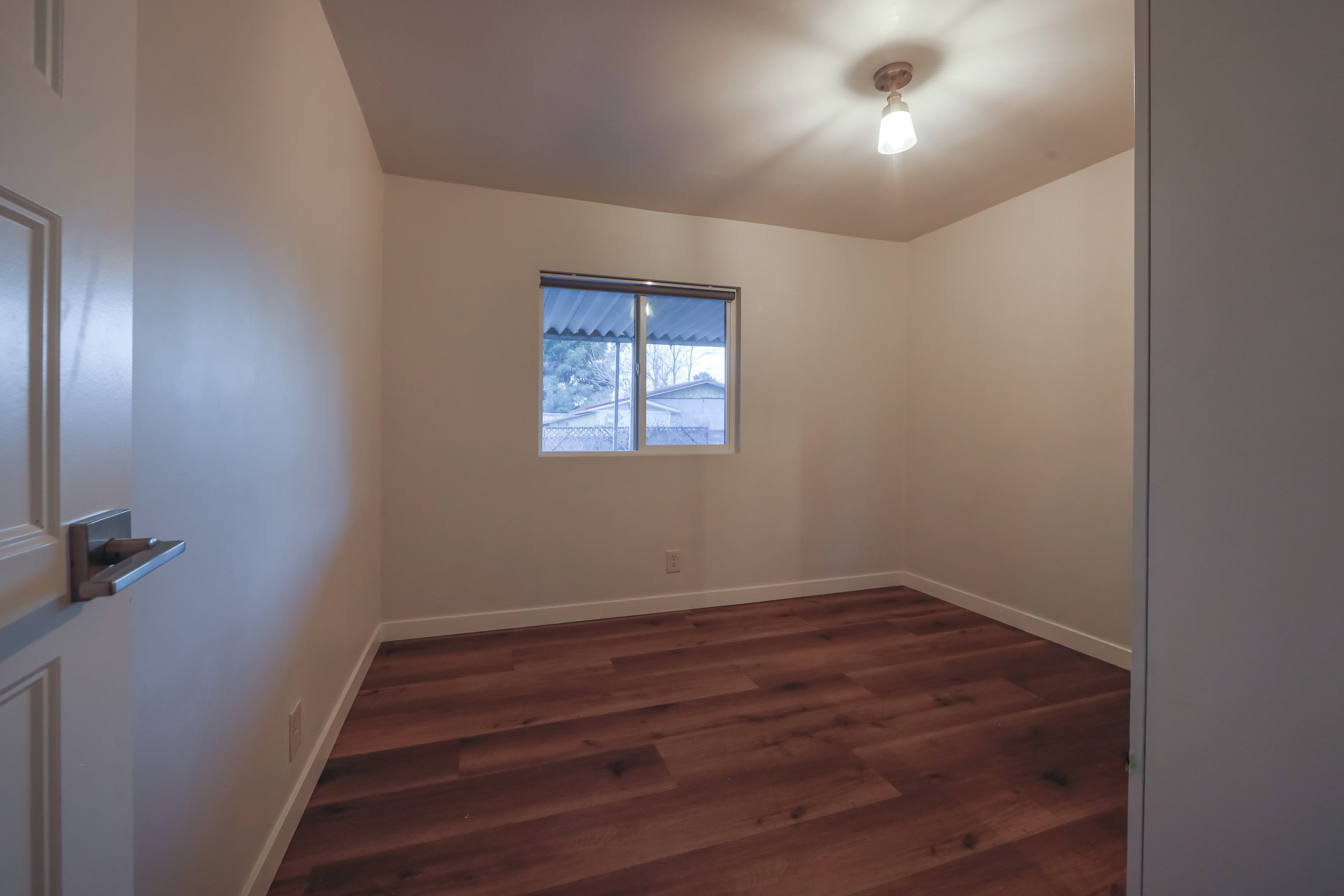 Empty room featuring dark wood finished floors and baseboards