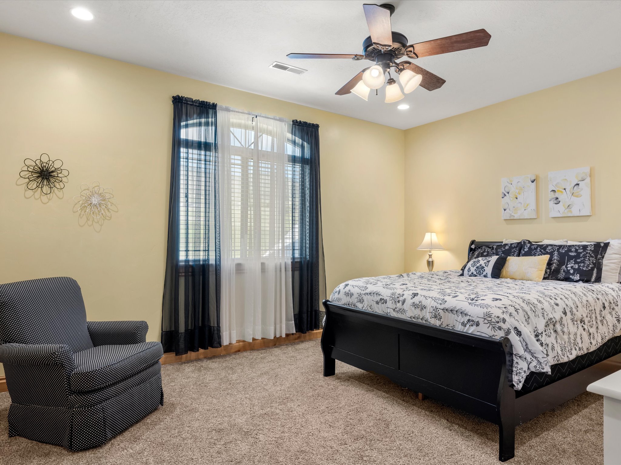 Neutral-toned walls and plush carpeting complement the ceiling fan with integrated lighting