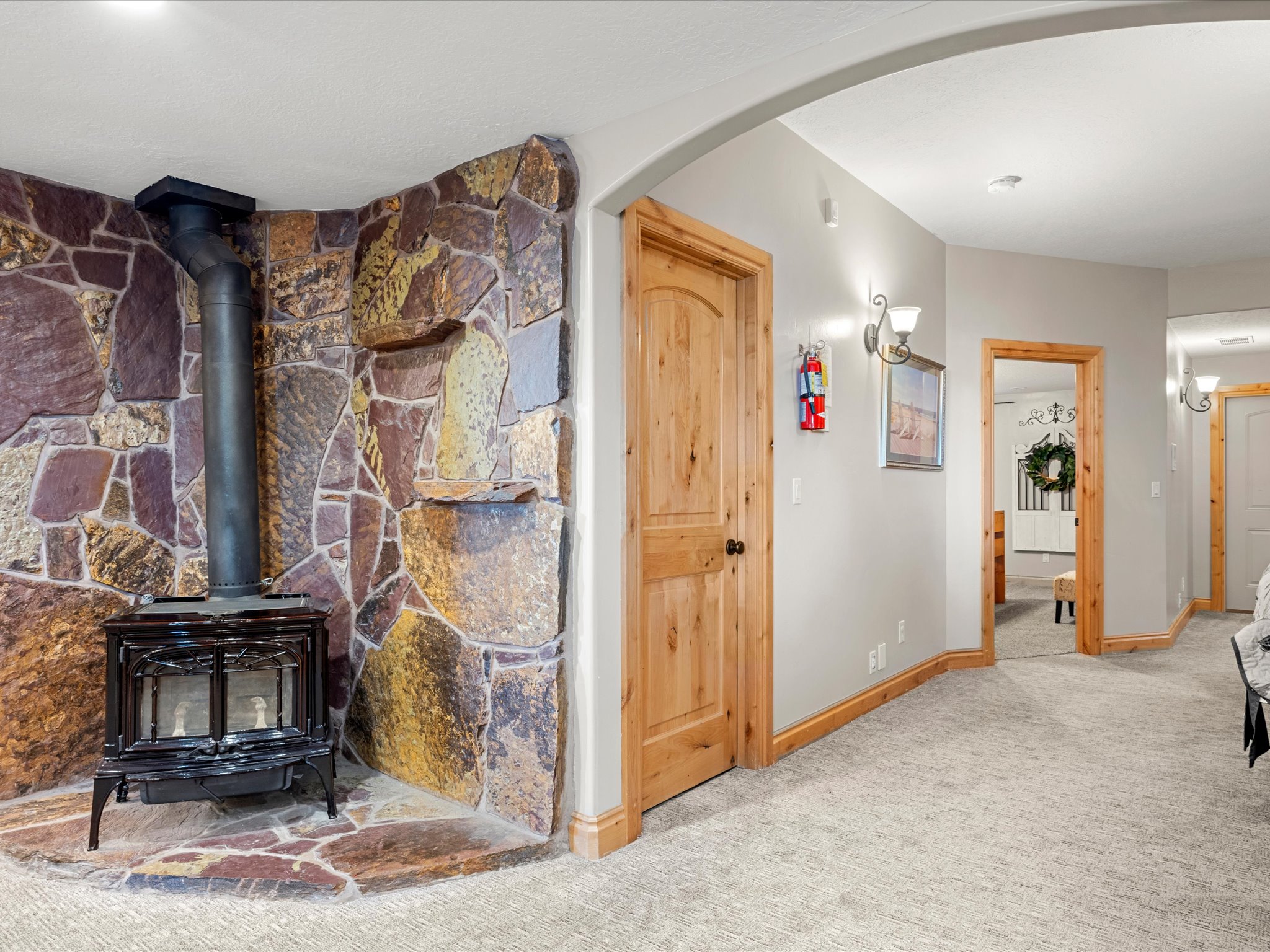 Stone accent wall featuring a black wood-burning stove with a metal flue
