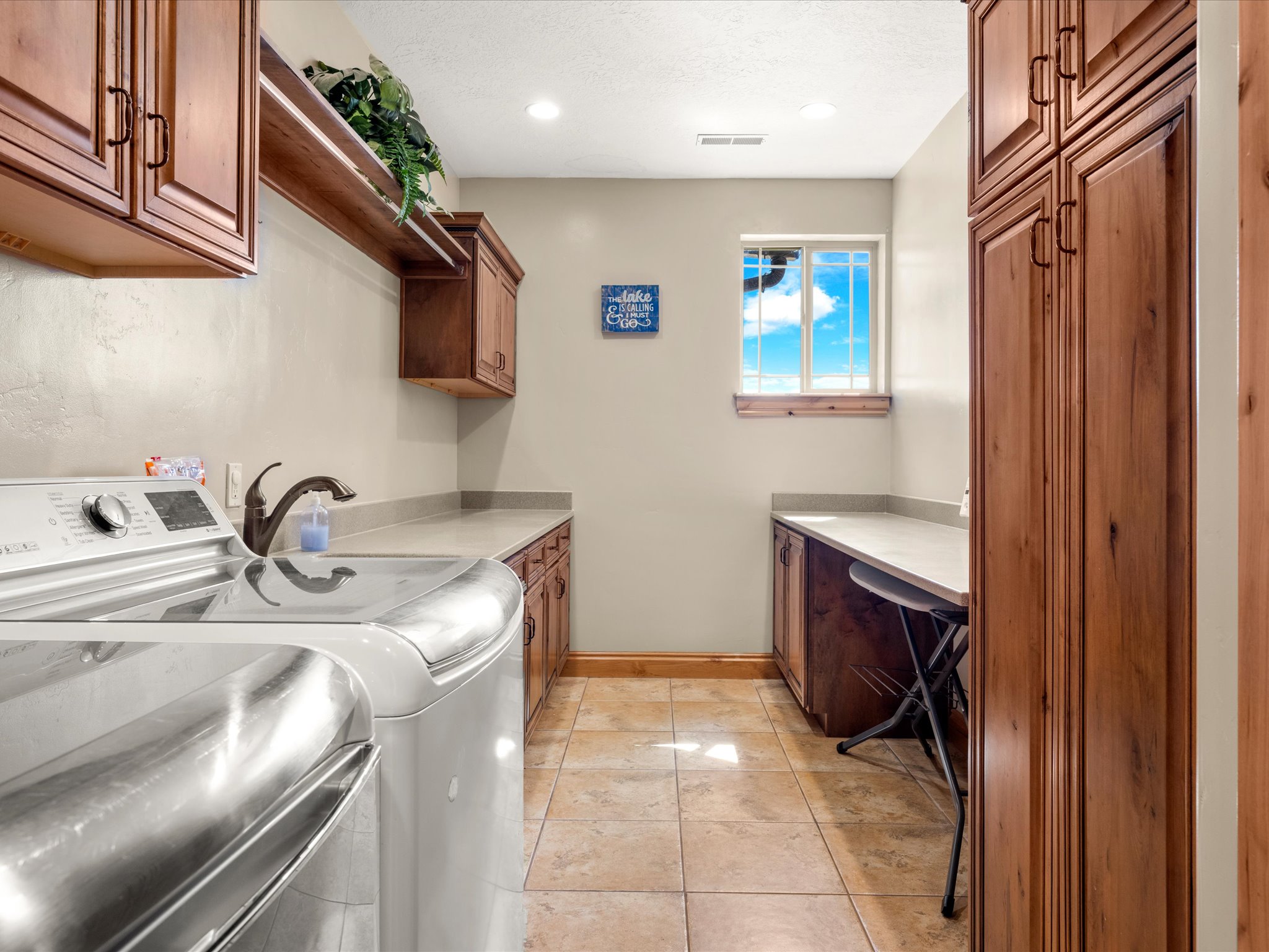 2nd floor Laundry area with extensive wood cabinetry, light-toned countertops, and tile flooring