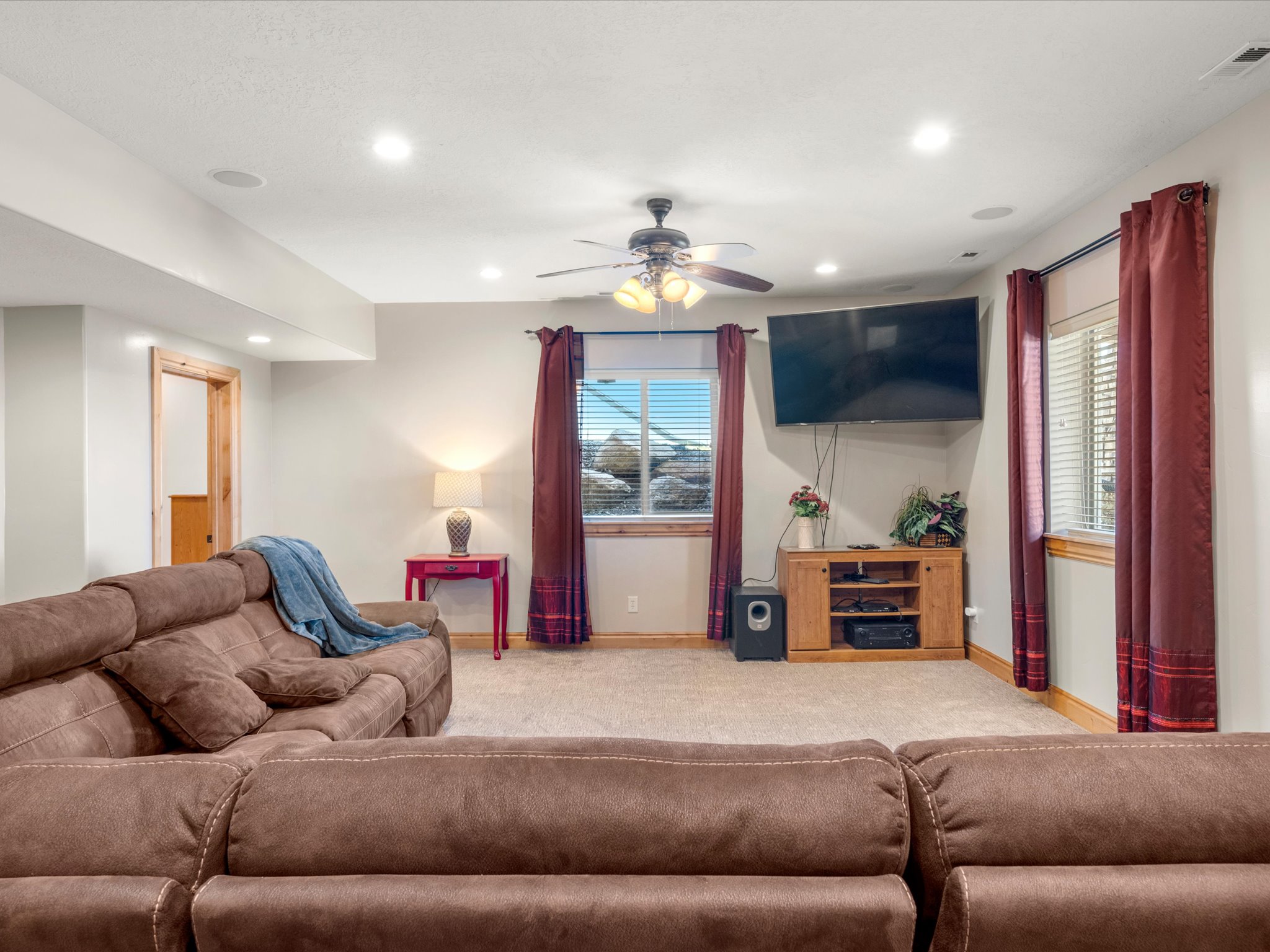 Carpeted entertainment area featuring recessed lighting, a ceiling fan, and two windows with blinds and curtain rods