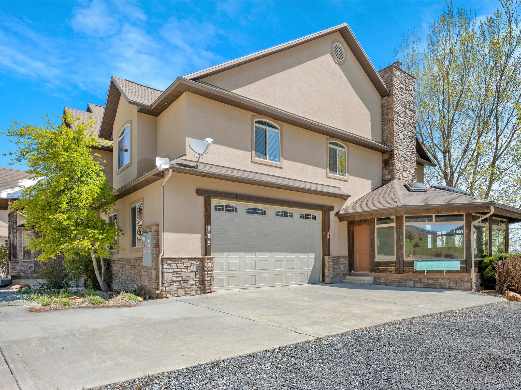 Stucco exterior with stone veneer accents, multi-pane windows, and an attached two-car garage