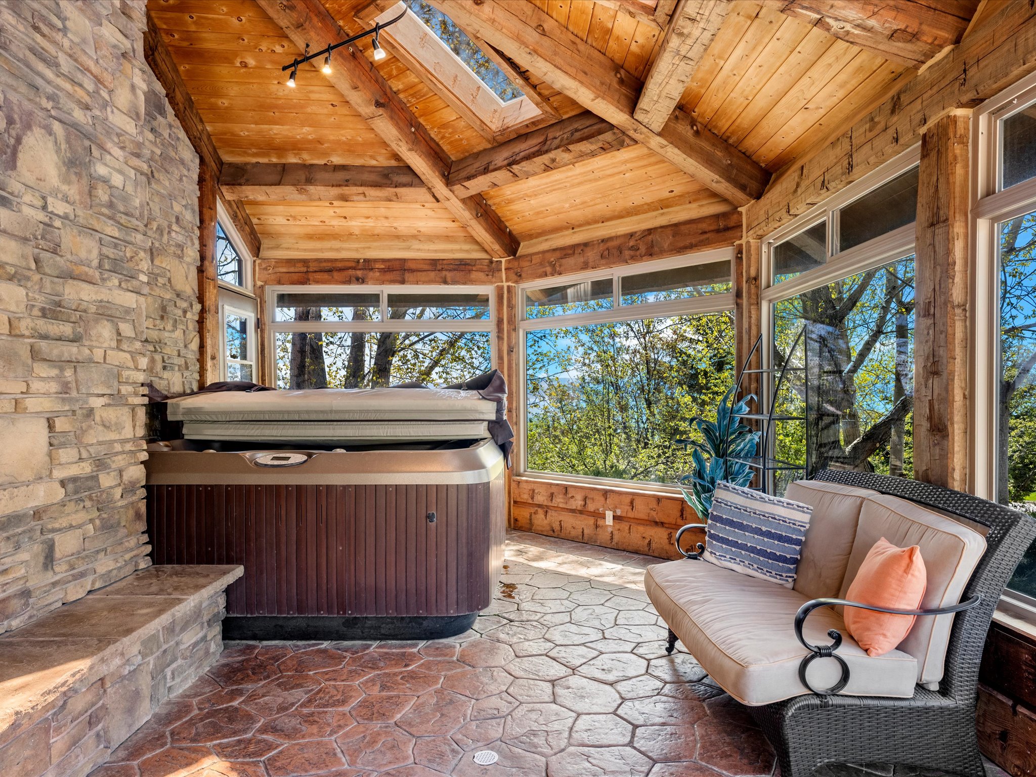 Sunroom featuring a hot tub, stone wall, vaulted wood-plank ceiling, and stamped concrete flooring