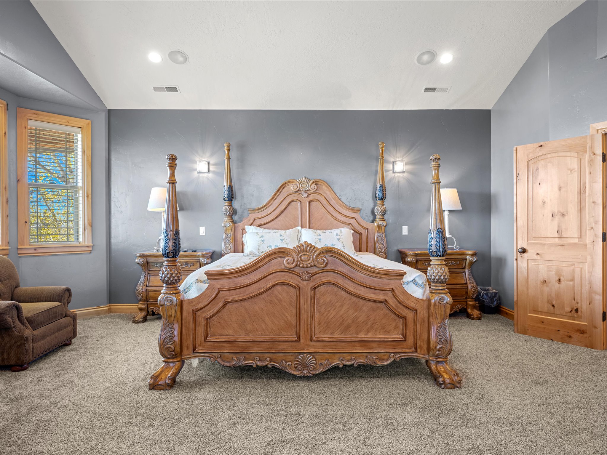 Spacious room featuring gray textured walls, recessed ceiling lighting, and light wood doors with black hardware