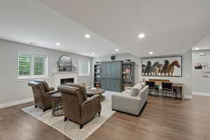 Spacious living area featuring wood-finish flooring, recessed lighting, and a white fireplace mantel
