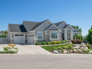 Contemporary residence featuring a light gray siding exterior with stone accents, multiple gables, and a prominent front entrance with white columns