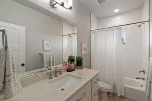 Main level Bathroom featuring a vanity with an integrated sink and light-toned countertop, brushed nickel faucet, a large wall-mounted mirror, and a shower/tub combination with subway tile surround
